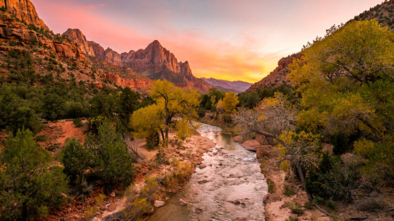 The rays of the sun illuminate red cliffs and river at Zion National Park.