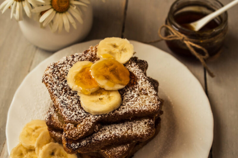 chocolate french toast with banana and honey on wooden background