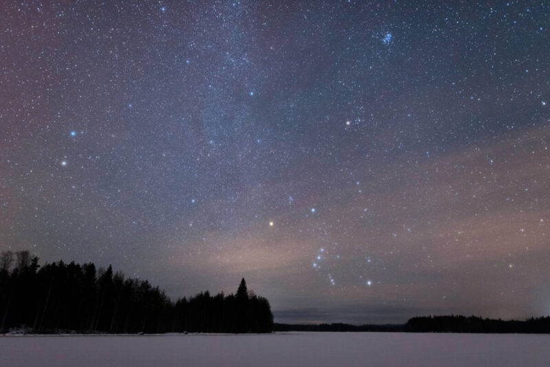 stars over a frozen lake including the constellation Orion