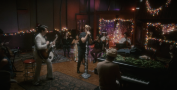 ryan gosling surrounded by musicians and christmas lights in music studio