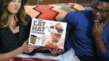 A woman and a man with a box labeled "cat hat" between them