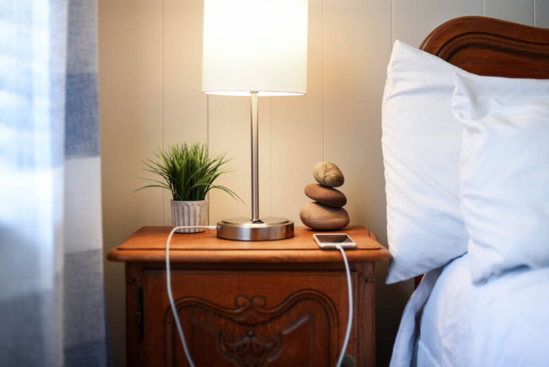 Smartphone plugged in on nightstand next to bed