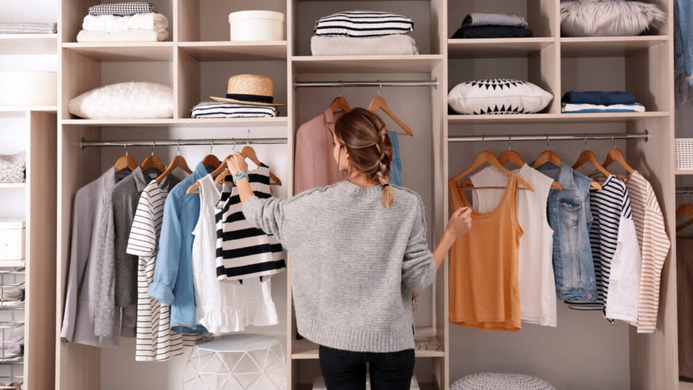 Woman choosing outfit from large wardrobe closet