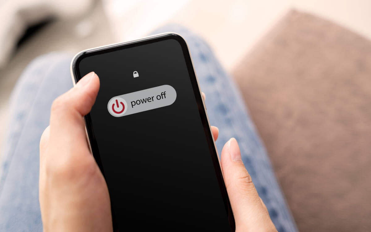 Woman’s hand about to turn off smartphone with “power off” slider on screen