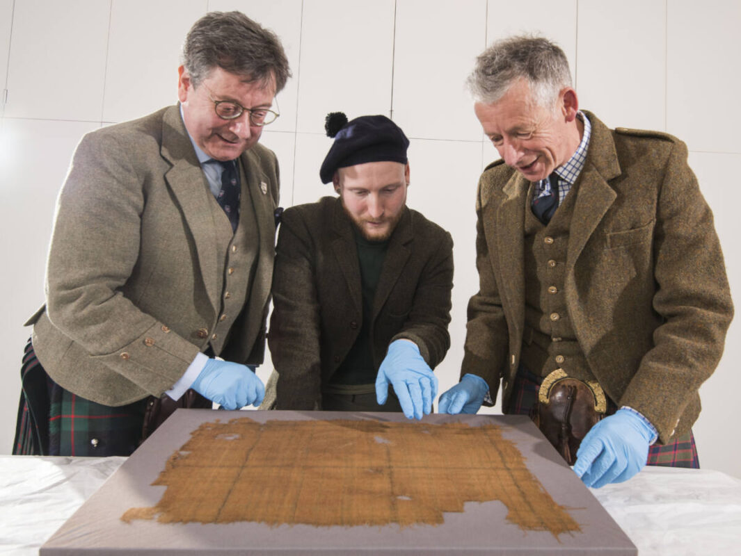 John McLeish and Peter Peter MacDonald inspect the Glen Affric Tartan with James Wylie of the Victoria and Albert Museum, Dundee, in center