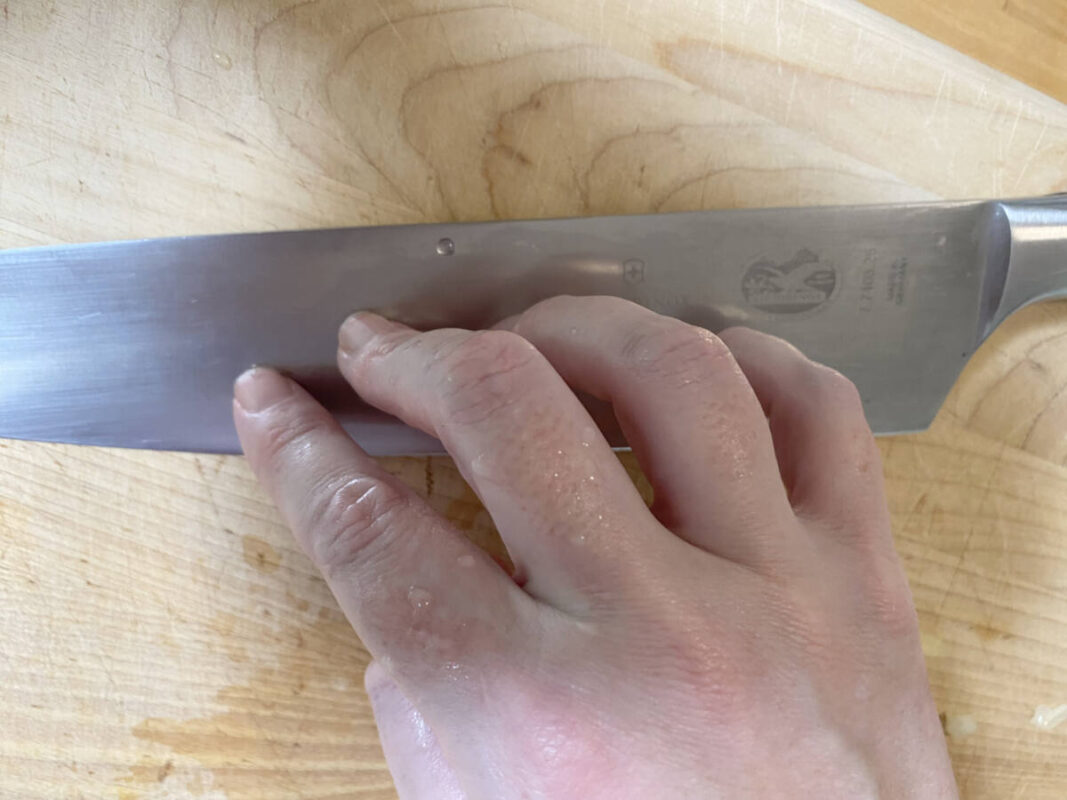 Writer rubs fingertips along flat blade of knife