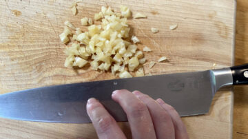 Chopped garlic and fingertips on steel knife