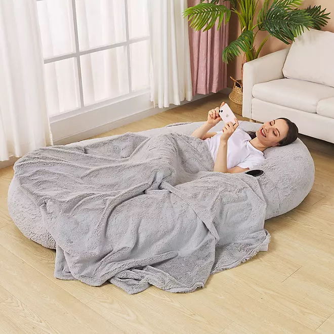 Person looking at phone while in dog bed big enough for human from Sam's Club