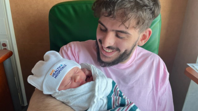 Rafael Abitbul holds his newborn son, the first baby born in NYC's Health System in 2024. The baby's doctor, Dr. Sherman Dunn, also delivered Rafael 23 years ago