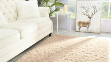 An area rug sits in front of a tufted white couch.