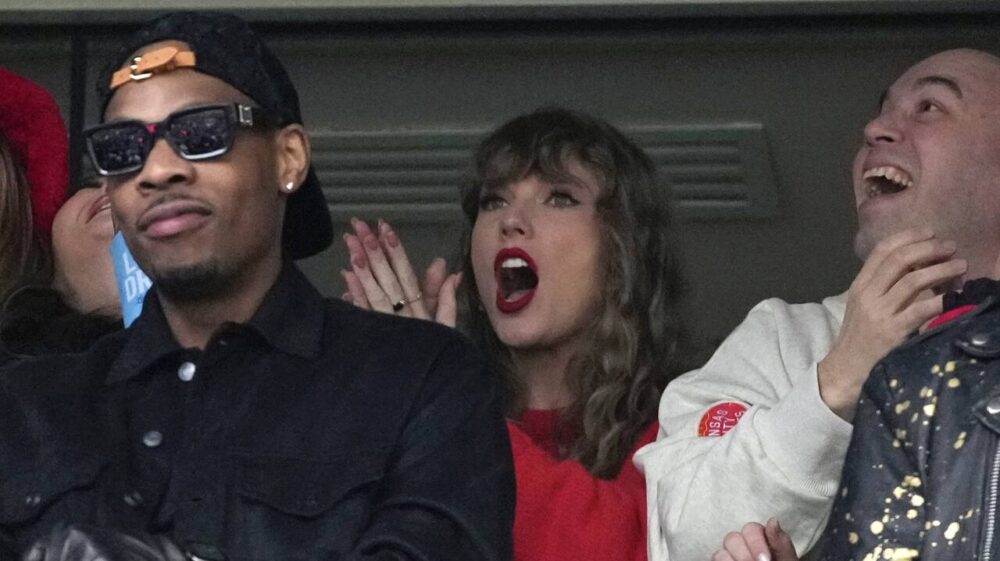 Aric Jones, left, stands in front of Taylor Swift at Chiefs game