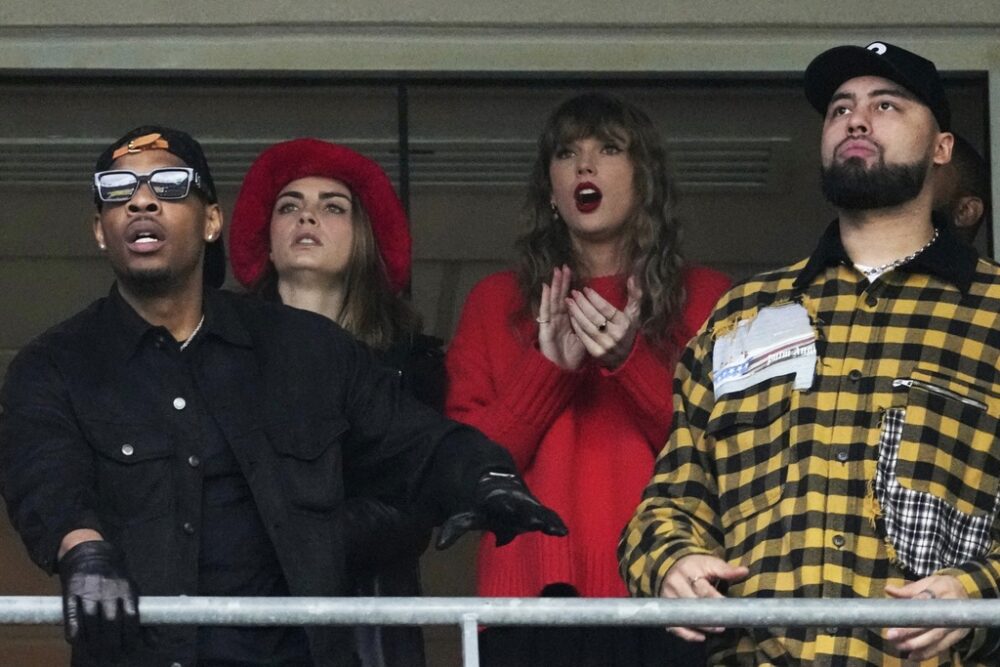 Aric Jones, left, watches football with Taylor Swift and other members of Travis Kelce's entourage.