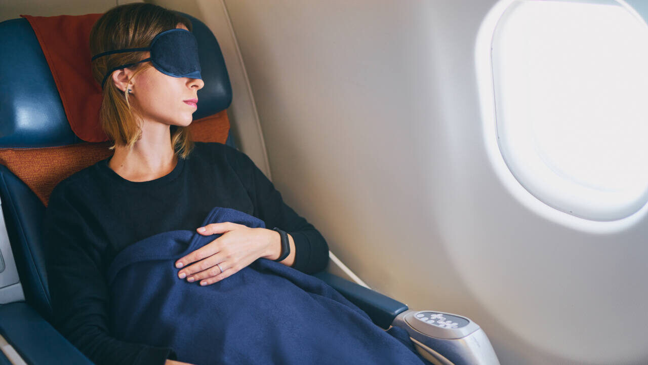 Airplane passenger sleeps with blanket