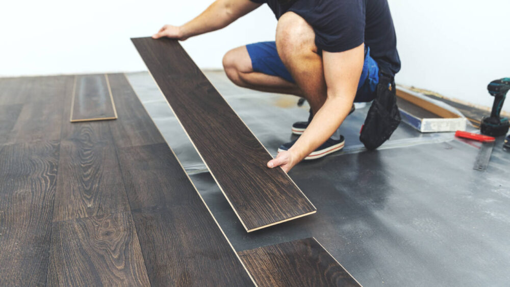 A person installs laminate flooring in a room.