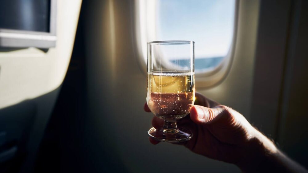 Airplane passenger holds glass of wine