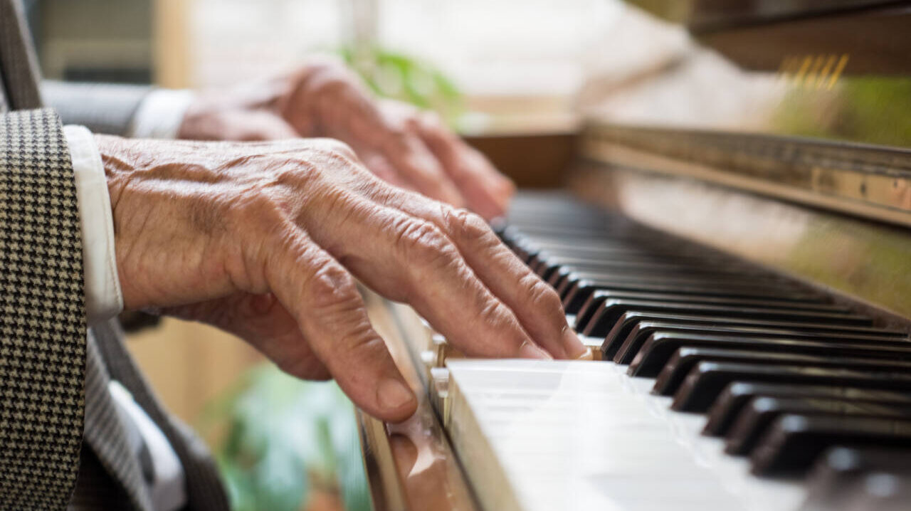 Older person's hands shown playing piano