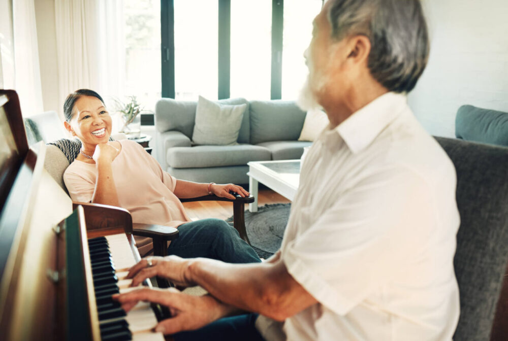 Senior man plays piano at home for woman