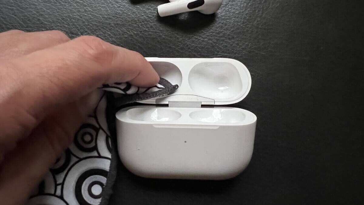 A person uses a lint free cloth to clean an airpods pro case.