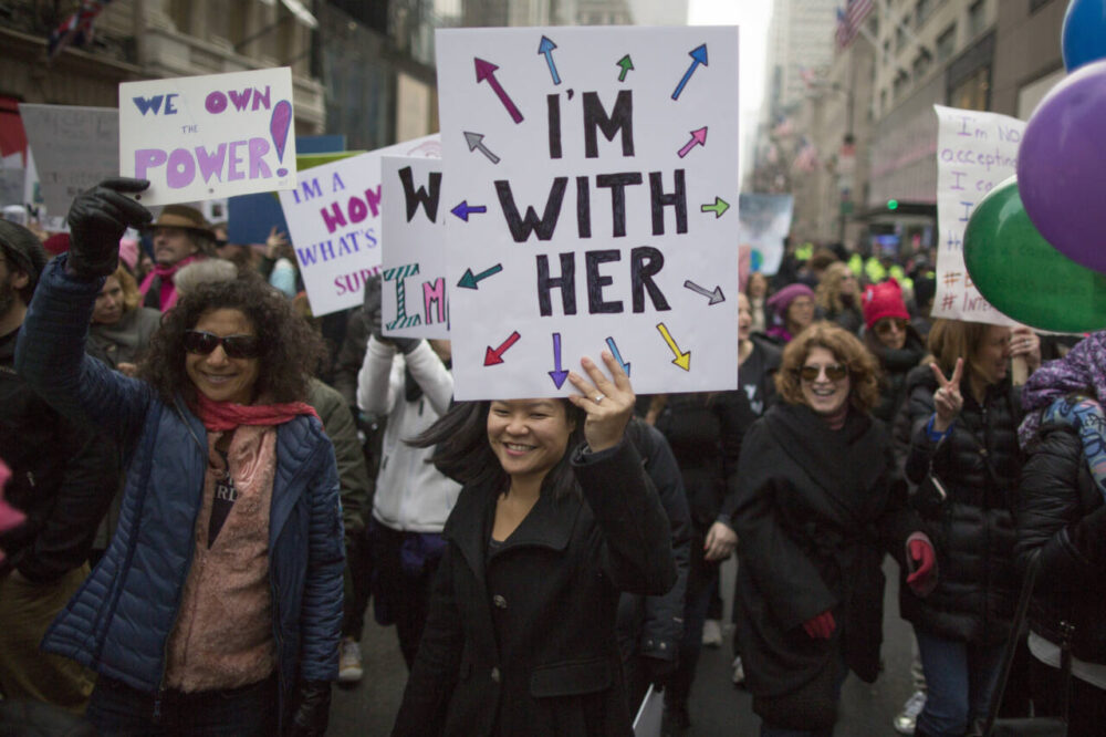 Woman holds 'I'm with her' sign in march