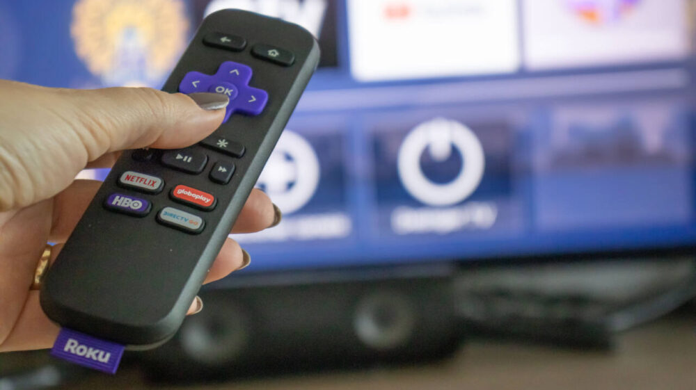 Woman pointing Roku remote at TV