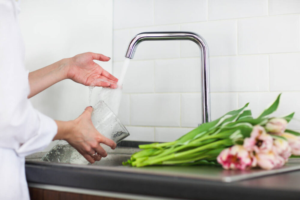 Woman filling vase with water for cut tulips