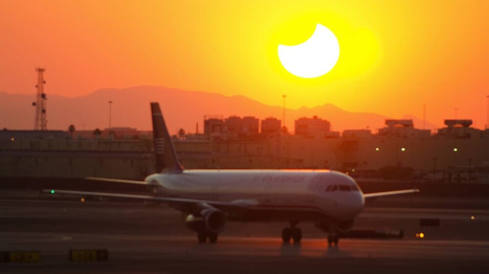 Solar eclipse as sun sets behind airplane at airport