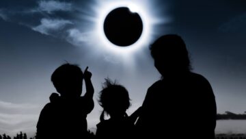 silhouetted family looking at eclipse