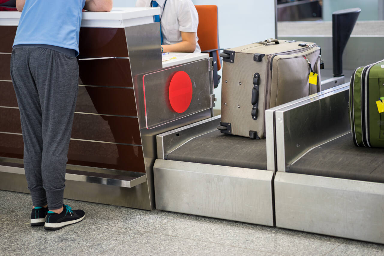 A customer checking luggage at an airport counter 