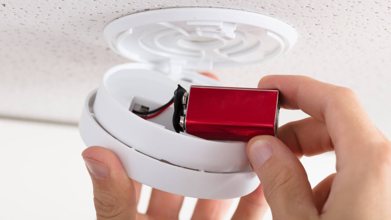 Person inserting a new battery into a smoke alarm