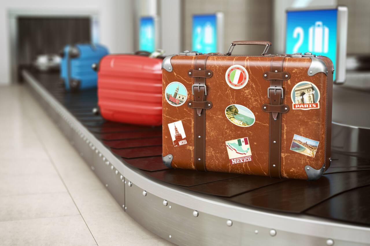 A brown suitcase with stickers on an airport conveyer belt 