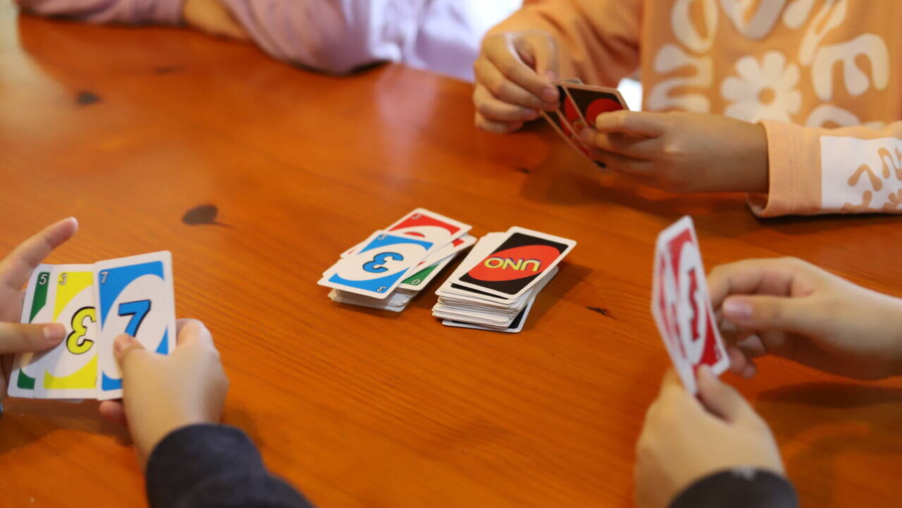 Group of children sitting around a table playing UNO
